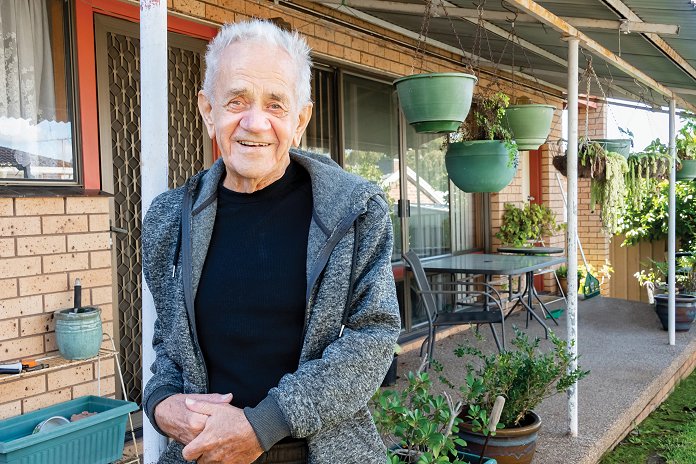 Older man standing in front of home