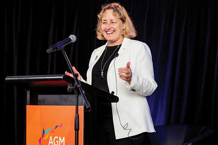 Woman standing and speaking on stage behind podium