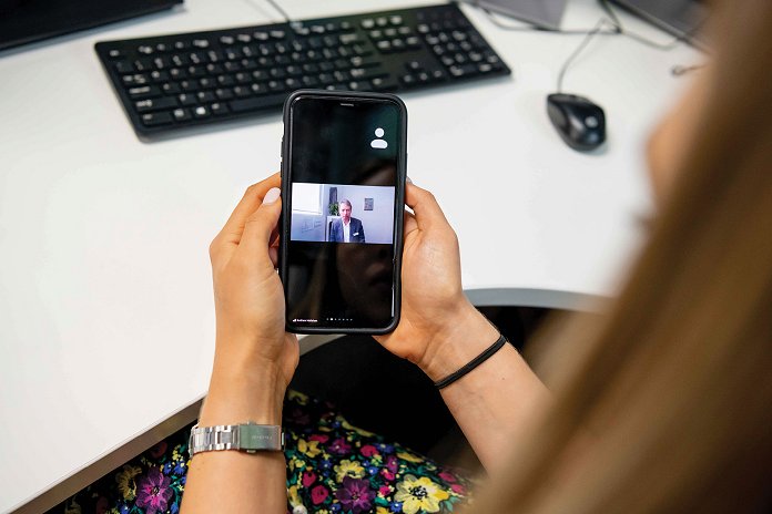 Woman at a desk holding a smart phone 