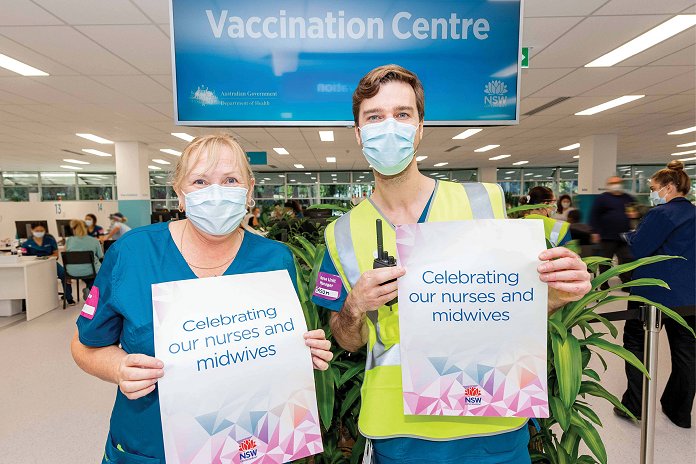 Two people wearing face masks holding up posters