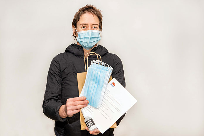 Woman with mask on holding a care package