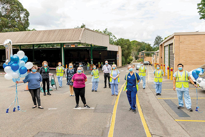 Group of people standing outdoors; socially distancing