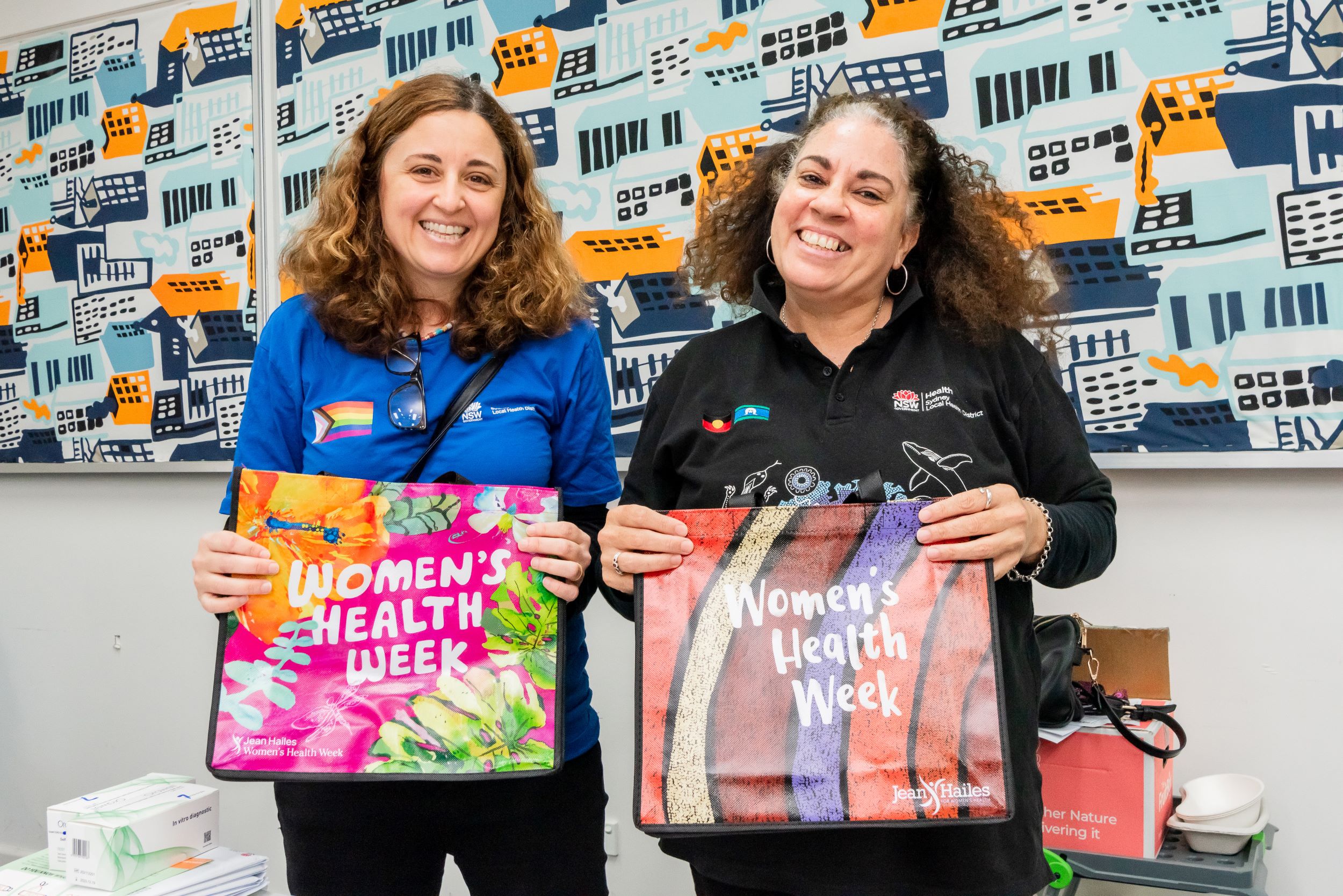 Two women standing together holding bags