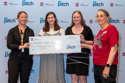 Four women standing holding a large prize cheque