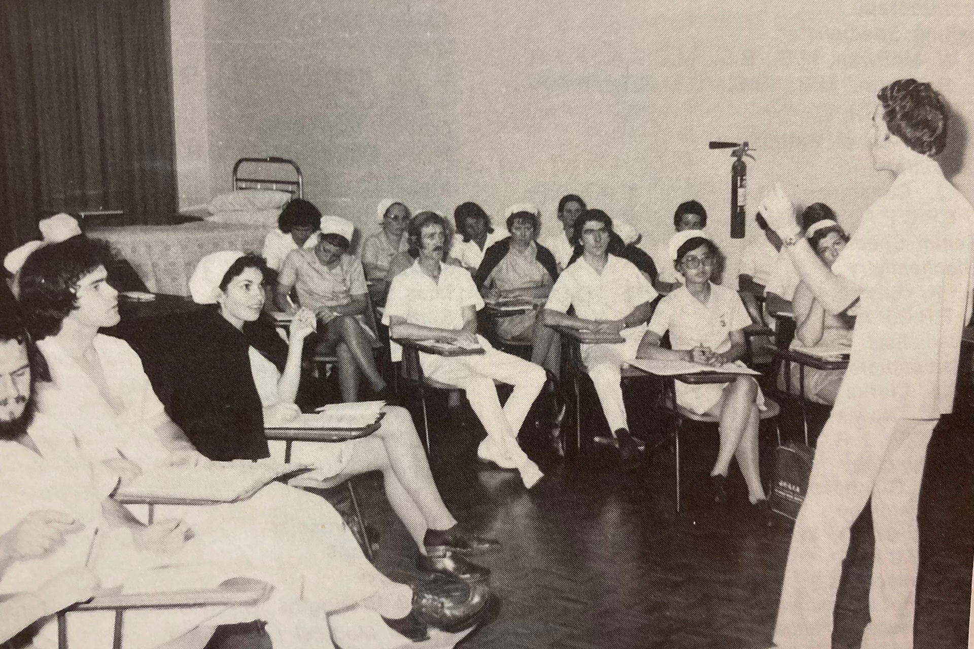 a black and white photo of a group of people and a presenter at front of room