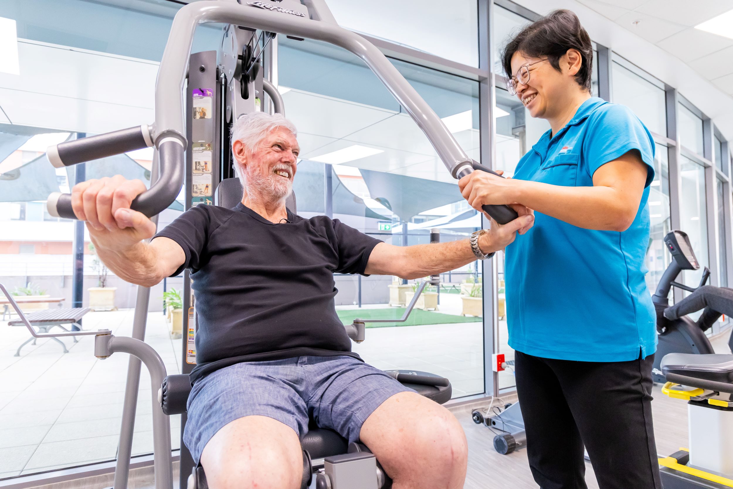 A patient uses exercise equipment while a staff member watches on.