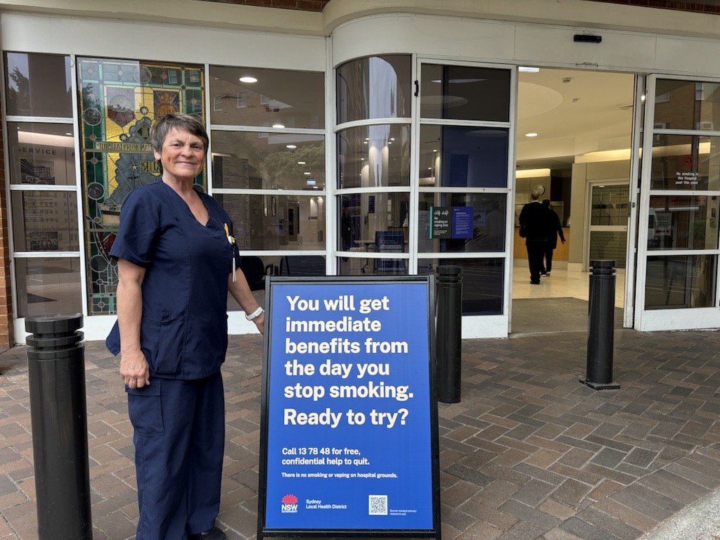 A nurse standing next to a sign talking about the benefits of quitting smoking