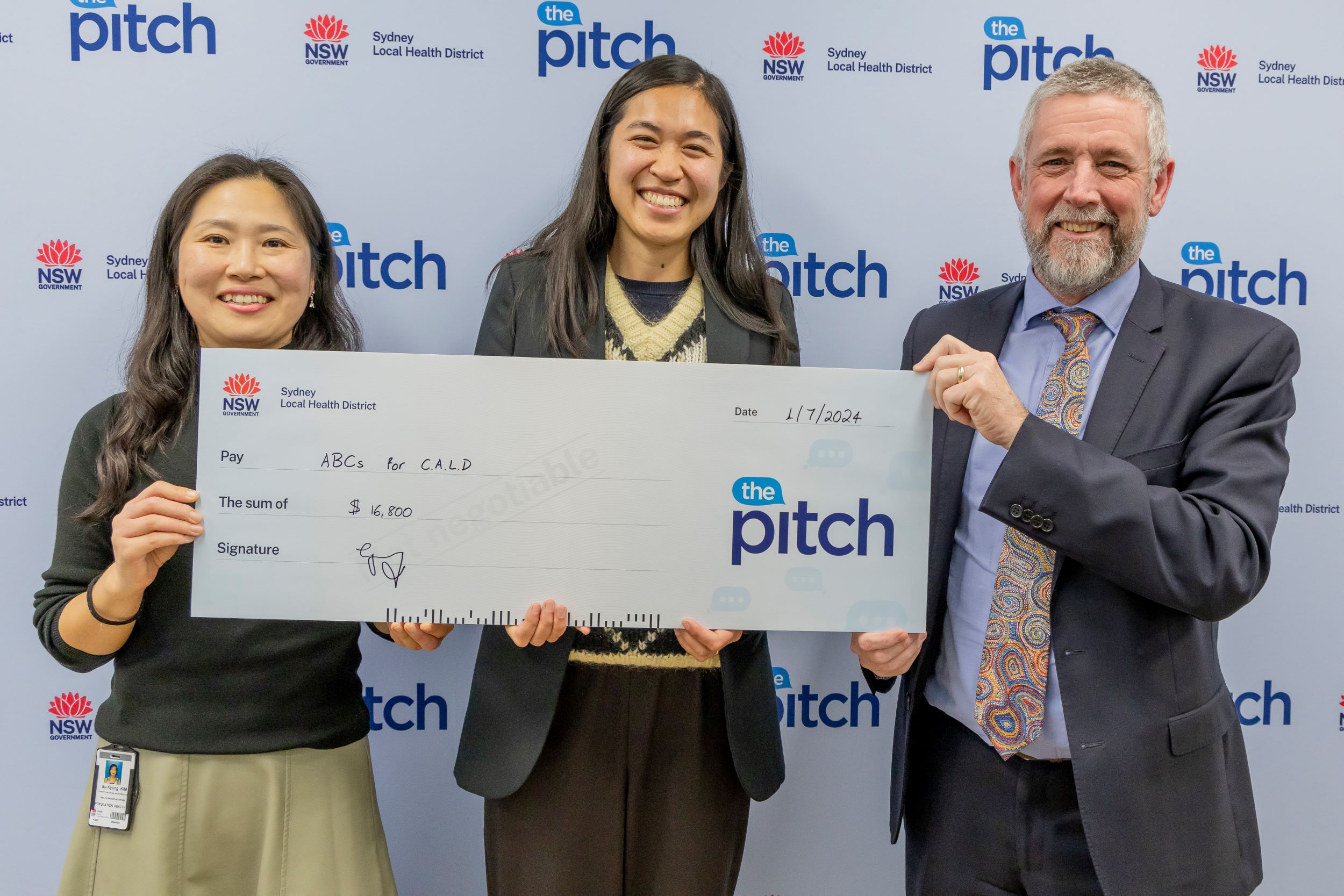 Three people holding a giant cheque