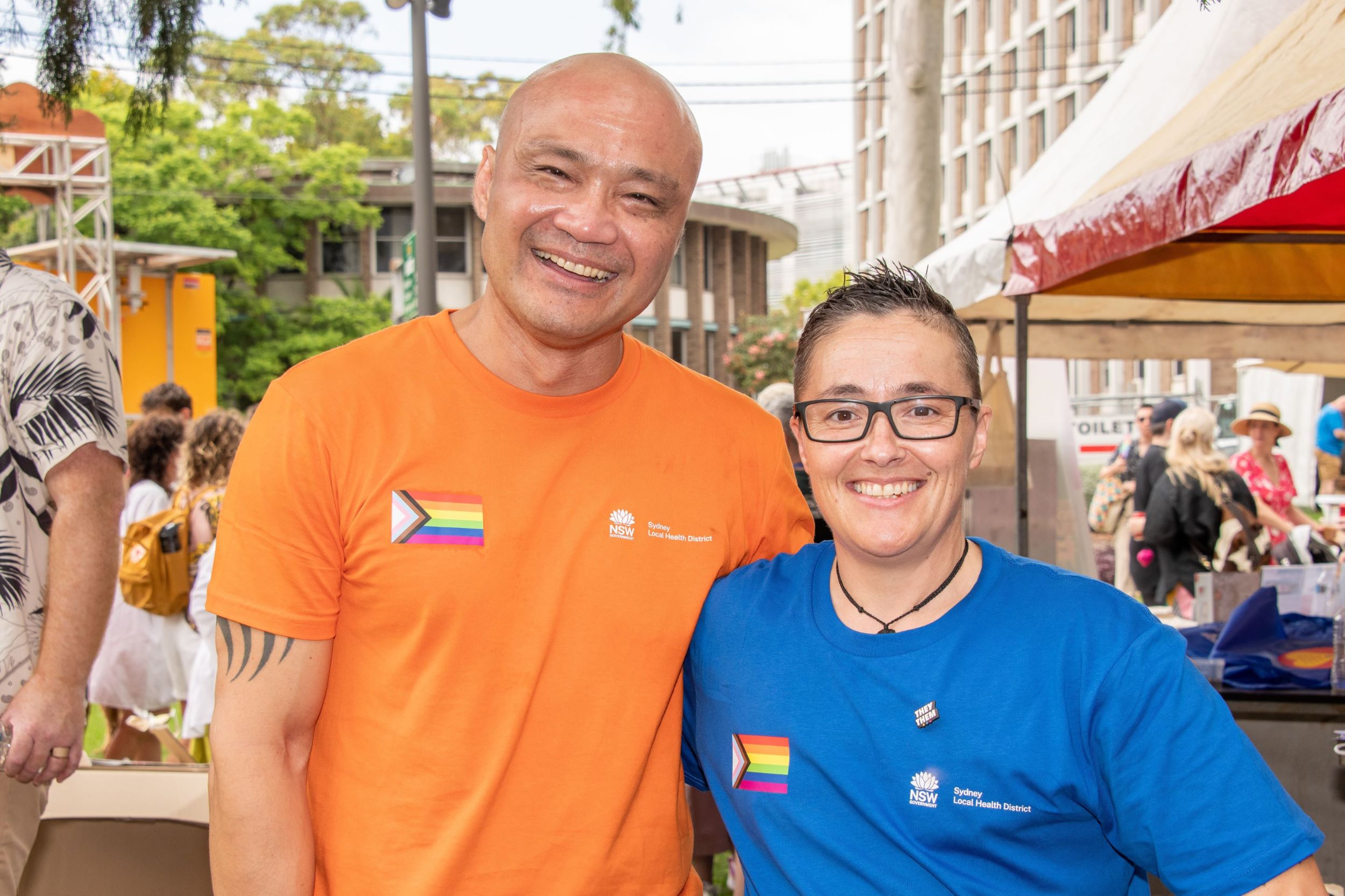 Two people stand together wearing t-shirts smiling at camera