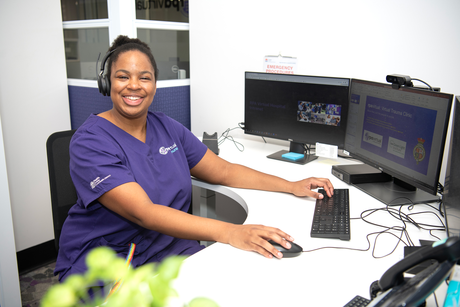 Virtual Trauma Clinic staff member in purple rpavirtual scrubs at computer