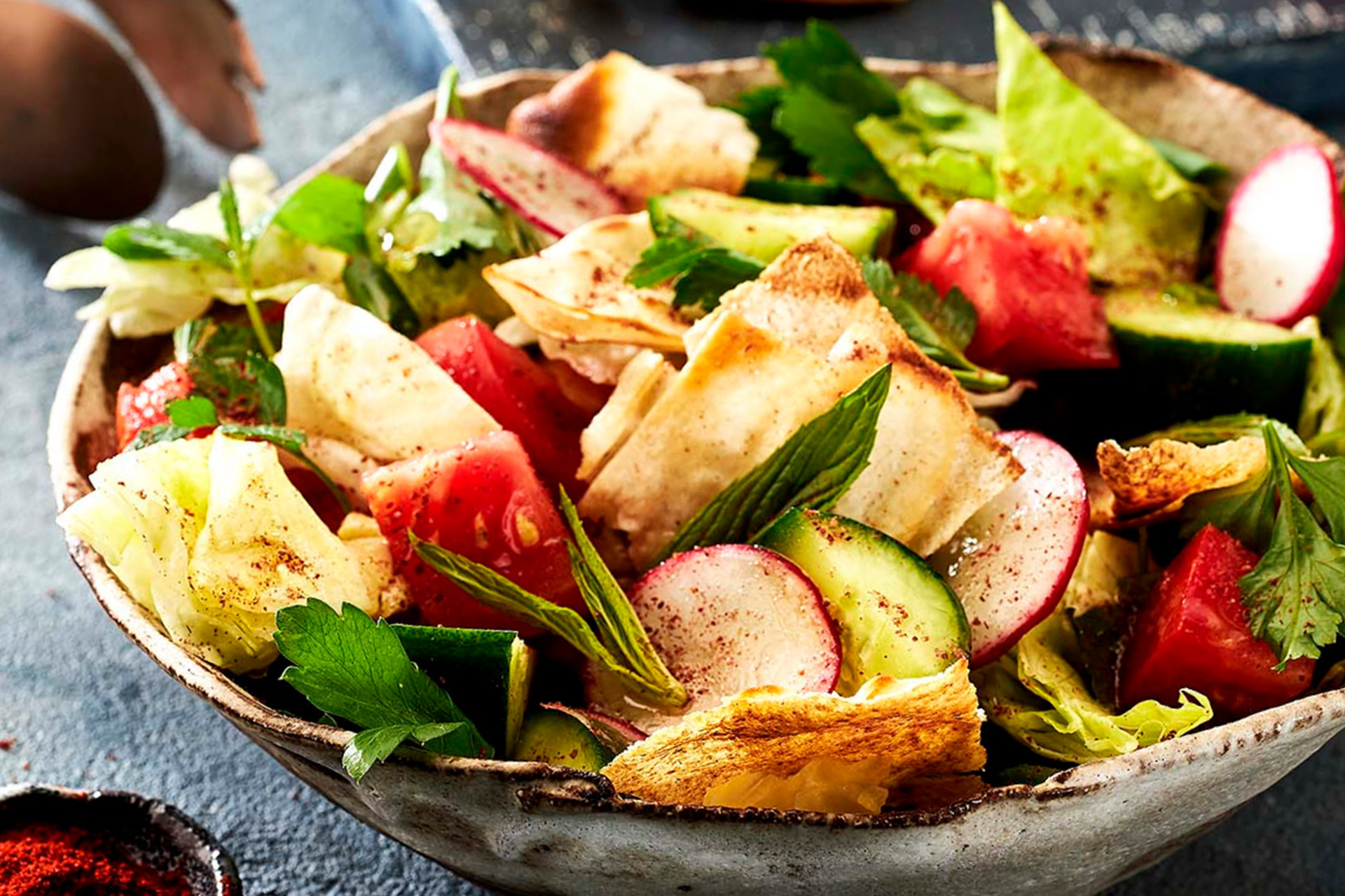 Fattoush served in grey bowl on charcoal bench