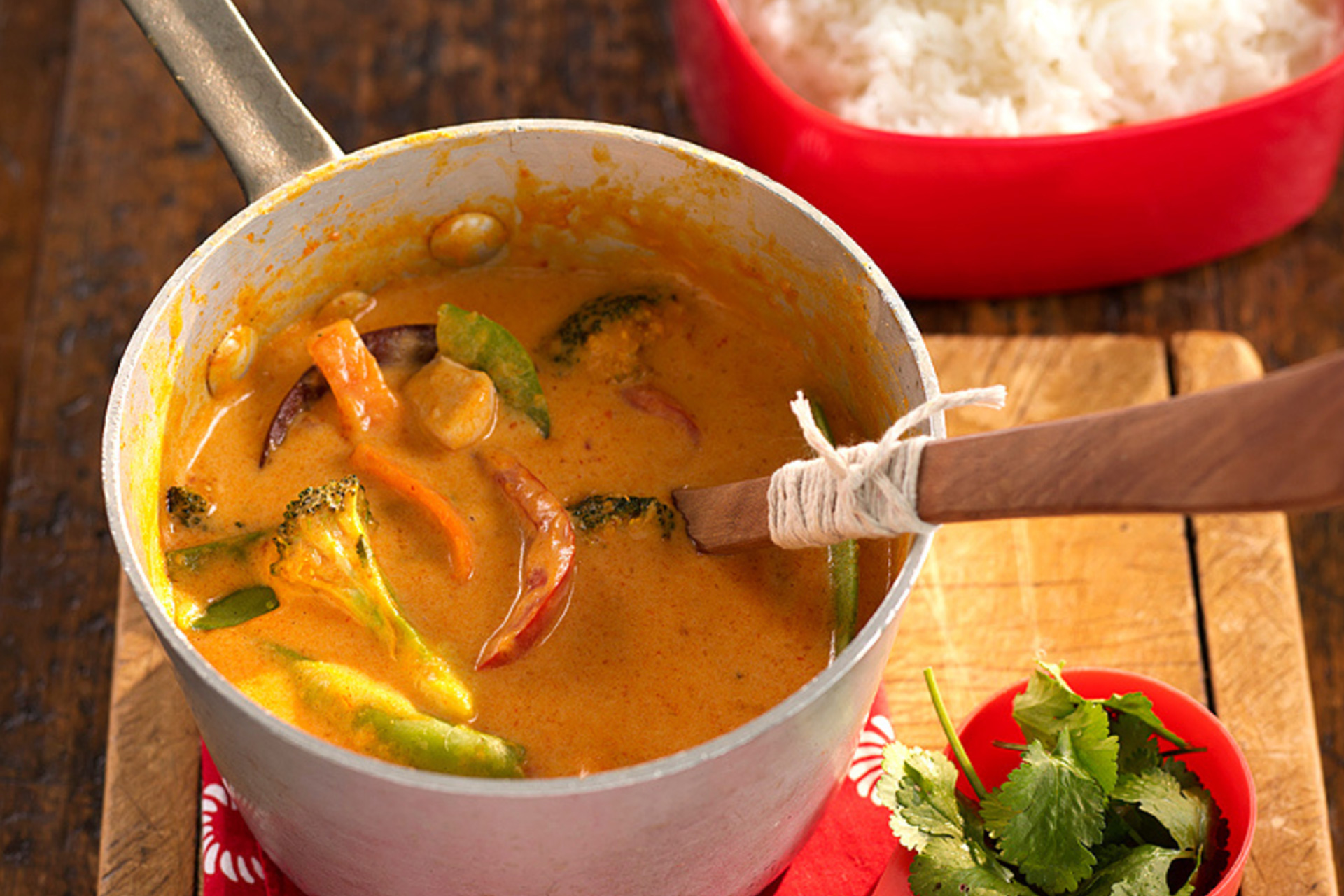 Thai red curry served in pot on wooden chopping board