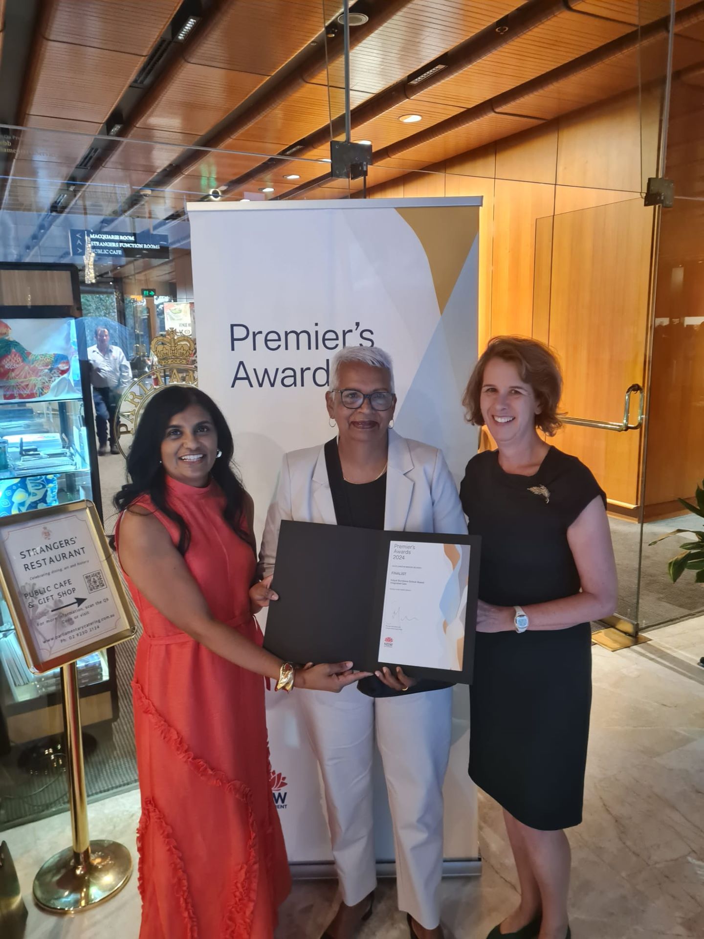 Three people standing together with an award