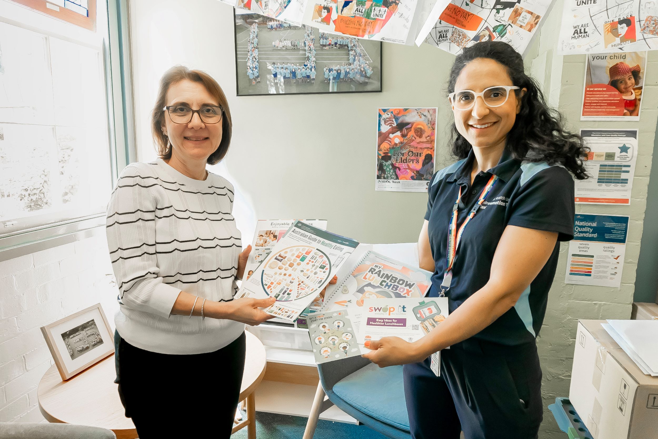 Two women standing together holding materials between them