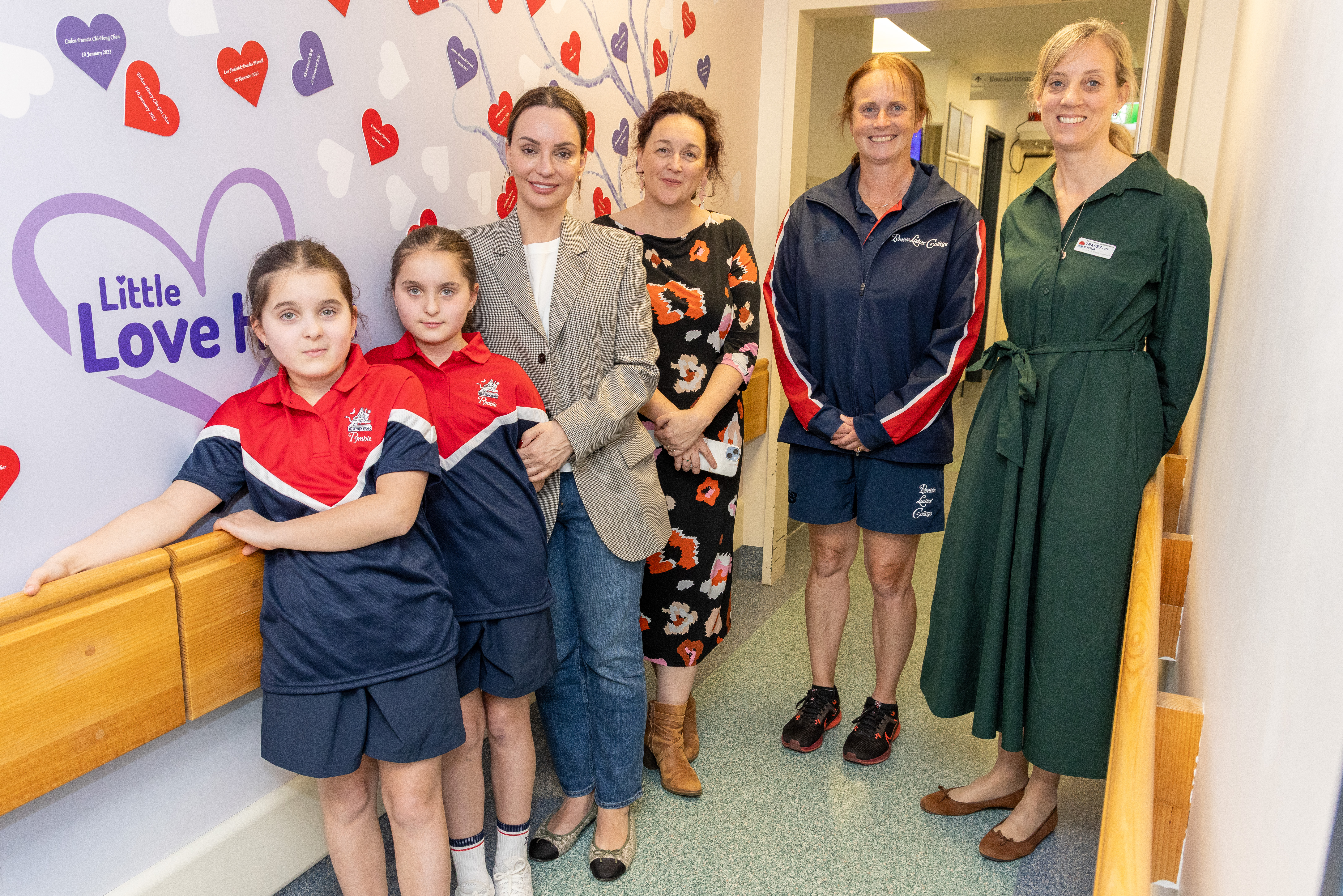 group photo of twins, their mother, their school teacher and NICU clinicians during visit to NICU