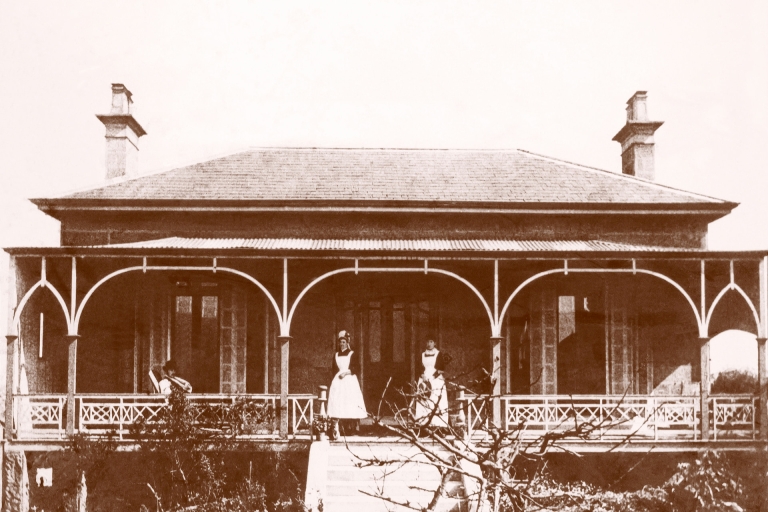 Black and white photo of two people standing outside a cottage