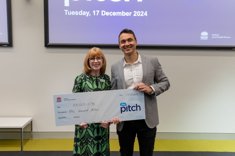 Two people standing next to each other holding a giant cheque