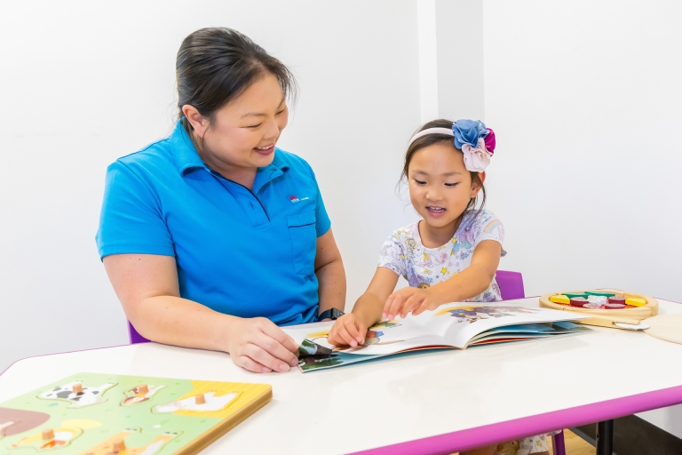 Community health staff and child reading a book