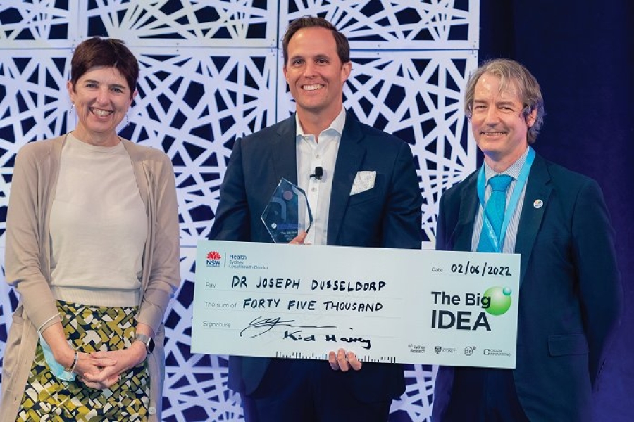 Three people on stage receiving a giant cheque reading: ‘The Big Idea. Pay Dr Joseph Dusseldorp the sum of forty five thousand.’