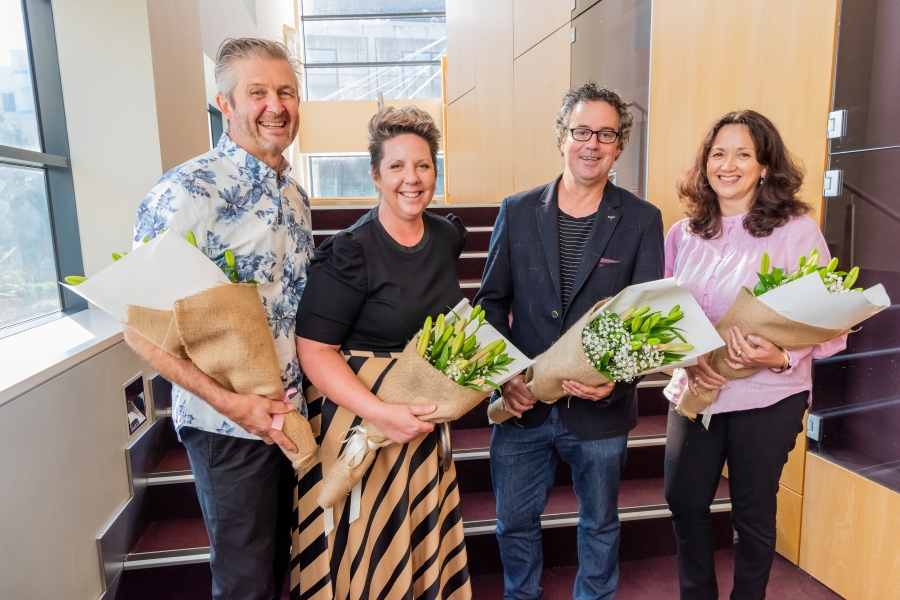 Four people with flowers standing in a row