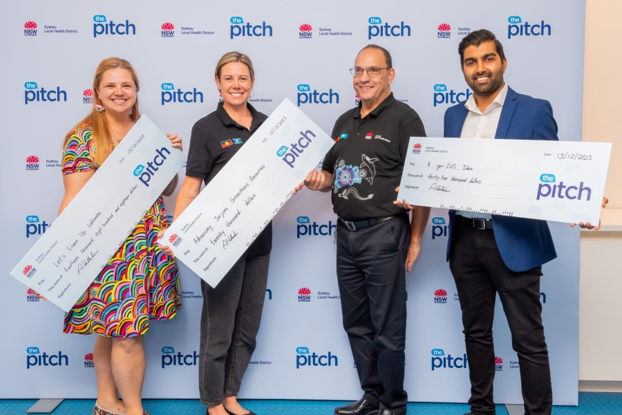 Four people standing holding a large prizemoney cheque each