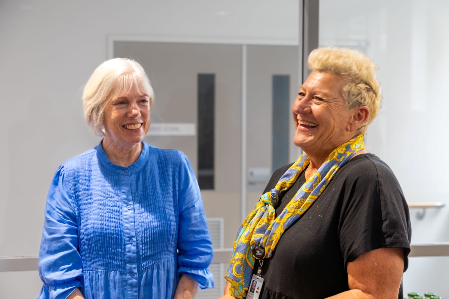 Two women stand together and are laughing. 