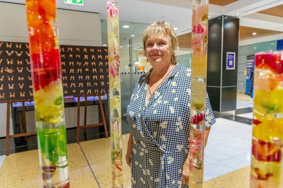 Woman standing amongst long poles of flowers in resin