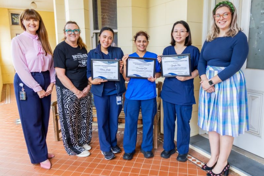 Six people stand together smiling, several people hold awards.