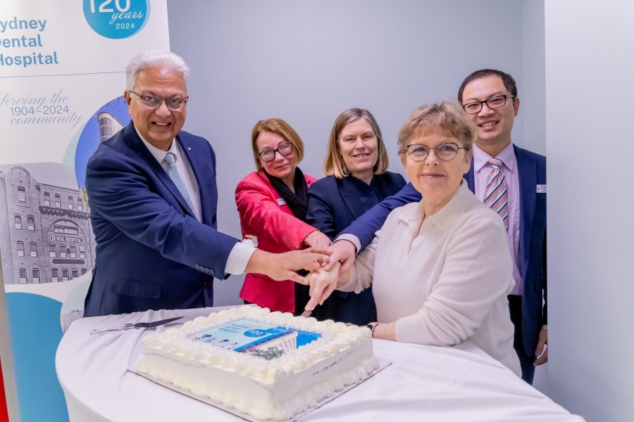 Group of people holding a knife together and cutting a cake
