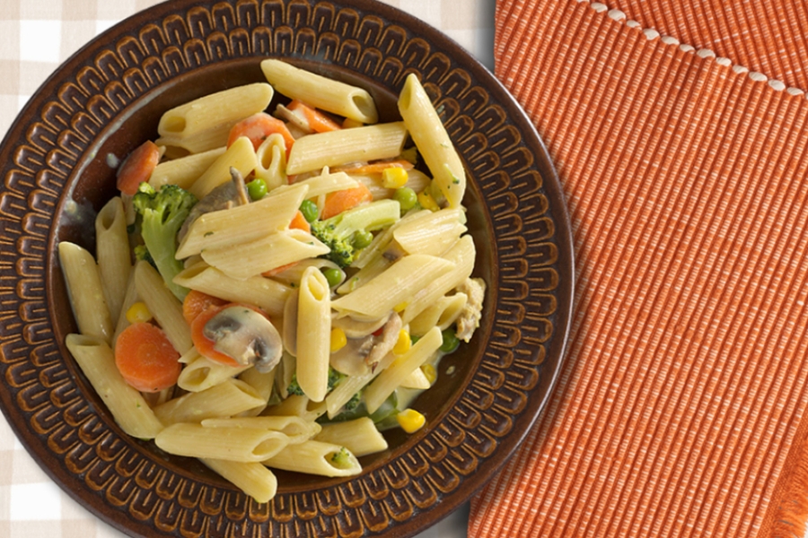 Creamy chicken pasta served in brown patterned bowl with orange napkin