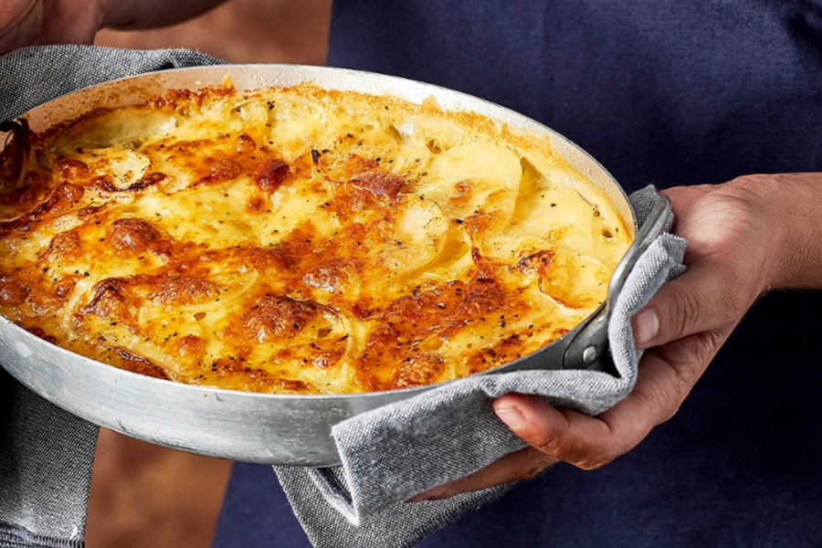 Hands holding tray of potato bake