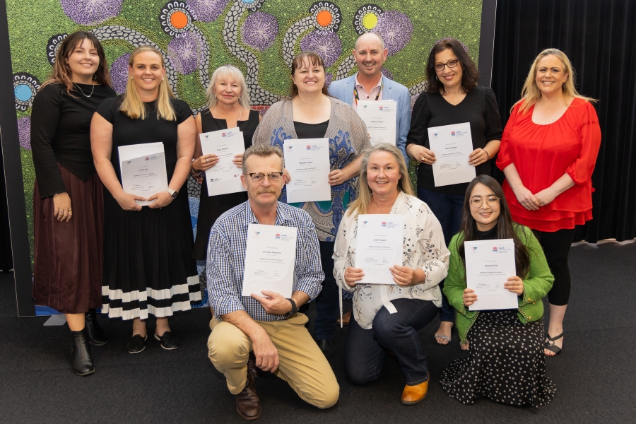 A group of people stand smiling at camera holding certificates