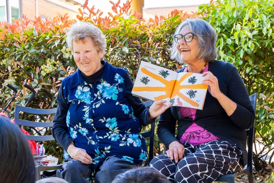 Photo of two Aboriginal Elders reading a story to a group of children