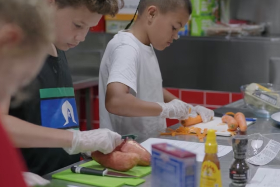 Young people in the kitchen peeling vegetables 