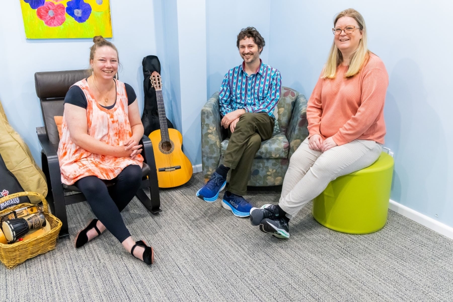 Three people sitting near each other indoors