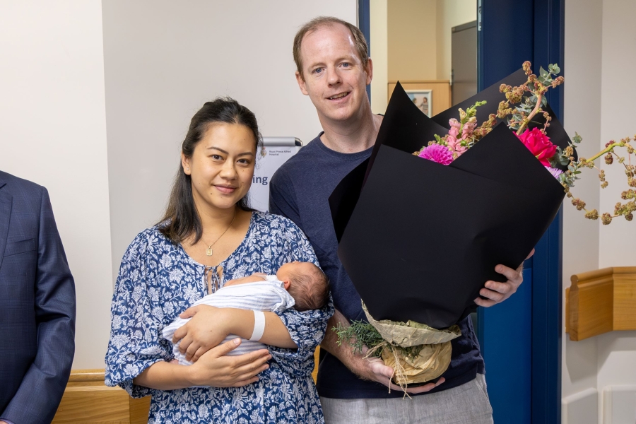 Couple holding their new baby and flowers