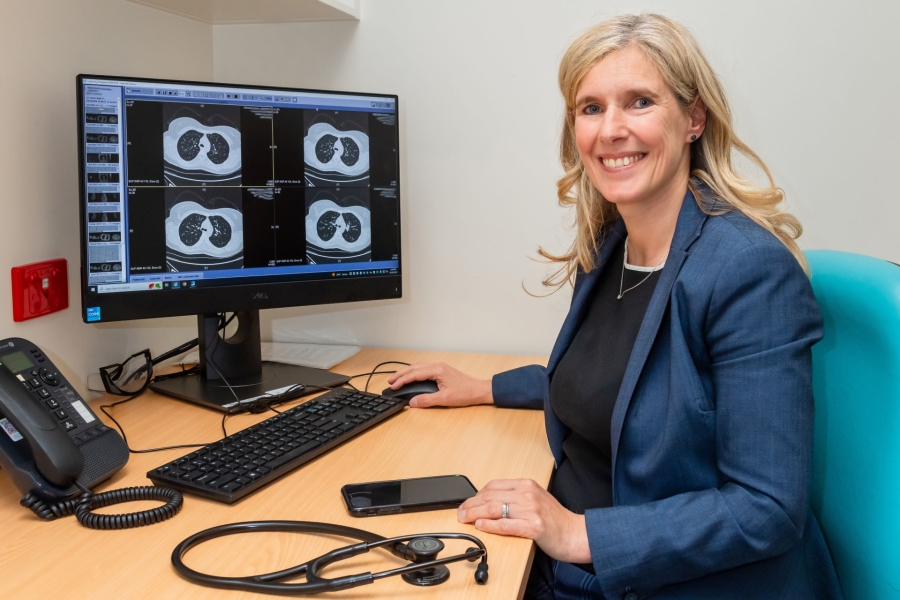 Doctor sitting at desk examining lung scans.