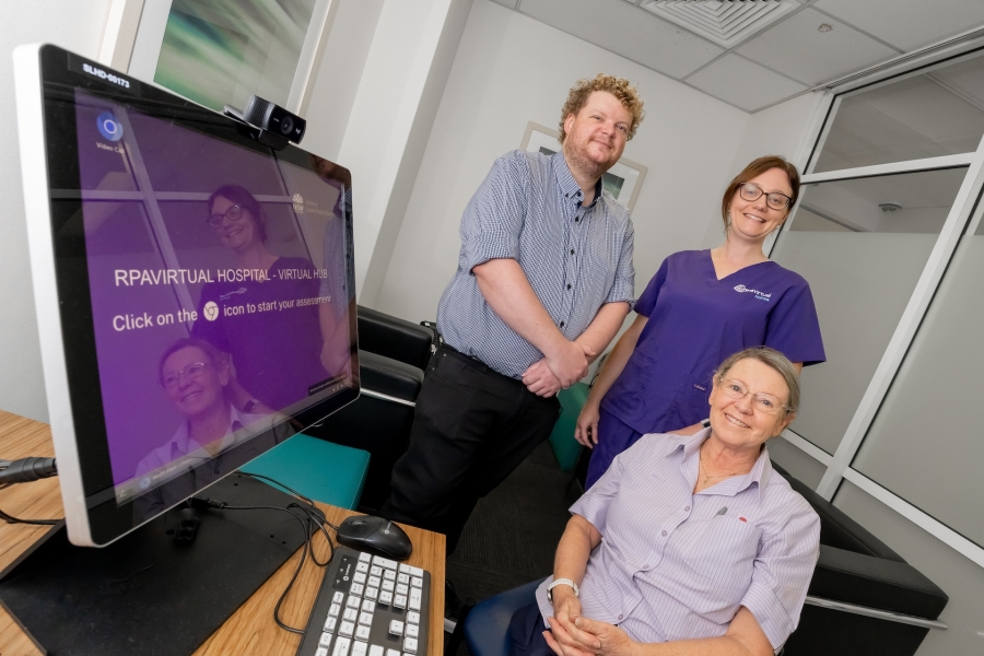 Photo of three clinicians smiling next to a computer
