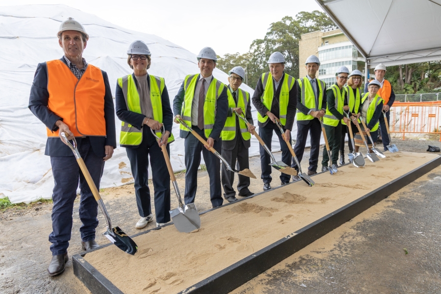 Group photo of 10 people wearing hight vis vests and holding shovels at a construction site