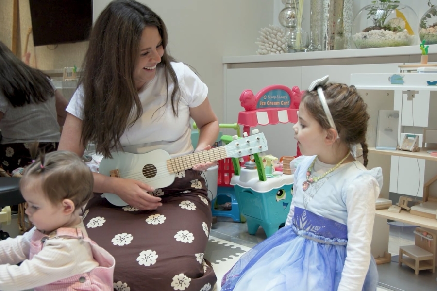 photo of patient Cynthia Parisi playing a small toy guitar for her children
