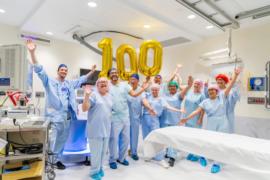 group of clinicians celebrate in front of balloons forming the number one hundred
